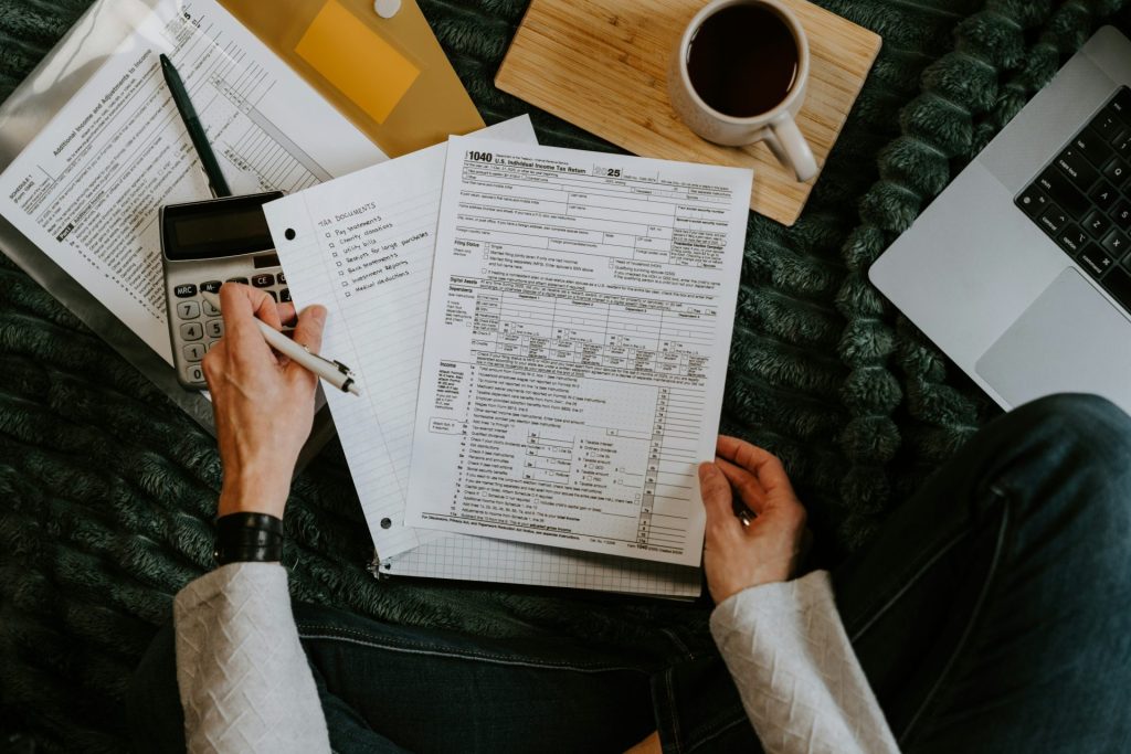 Personne consultant des documents à l'aide d'une calculatrice et d'un ordinateur portable.